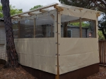 Custom-made transparent terrace enclosure made of beige tarpaulin with PVC windows, mounted on a wooden gazebo structure.