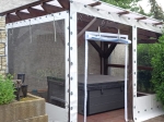Custom-made transparent terrace cover with white border, mounted on a wooden gazebo with a hot tub.