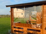 Protection de terrasse transparente sur mesure installée sur un belvédère en bois, protégeant du vent et de la pluie.