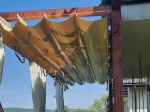 Золотиста горизонтальна римська штора ПВХ під замовлення, встановлена на дерев'яній конструкції садової перголи.