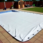 Wasserdichte weiße Plane nach Maß zur Abdeckung eines rechteckigen Gartenpools mit sichtbaren Metallösen.