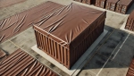 Custom-made brown tarpaulin, precisely fitted to a shipping container at a transshipment yard.