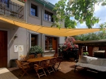 Velă de umbrire HDPE 3x3x4,2 întinsă peste o terasă cu mobilier din lemn și un leagăn confortabil.