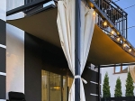 Vela de sombra impermeável quadrangular por medida instalada como cobertura de terraço numa casa moderna.