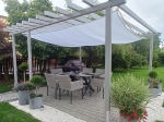 Wit waterdicht schaduwdoek vierhoek op maat gemonteerd onder een moderne tuinpergola.