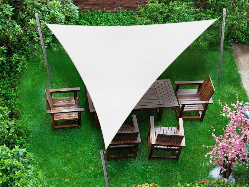 White triangular premium waterproof shade sail 3.5x3.5x3.5 m over a wooden garden furniture set on the grass.