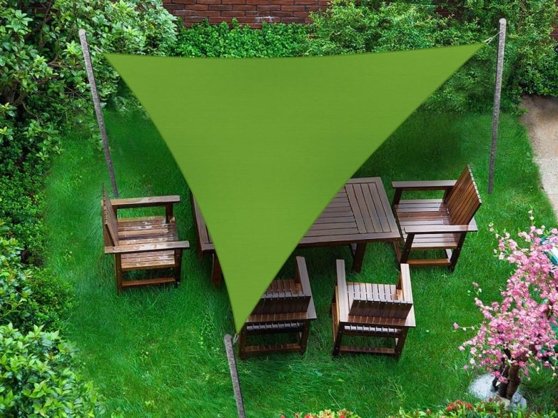 Green triangular premium waterproof sun sail over a wooden garden furniture set on the lawn.