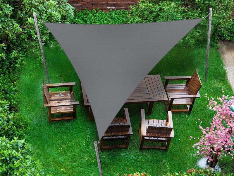 Yeşil çim üzerinde ahşap bahçe mobilyalarını koruyan gri üçgen premium su geçirmez güneş yelkeni 5x5x7.