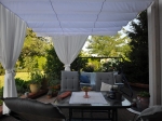Λευκό οριζόντιο ρωμαϊκό στόρι premium Decor διαστάσεων 3x4 m τοποθετημένο σε βεράντα πάνω από σετ επίπλων κήπου.
