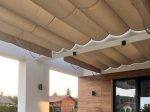 Μπεζ οριζόντια ρωμαϊκή ρολέτα premium Decor 3x4 σε βεράντα με λευκές κολώνες και ξύλινη πρόσοψη.