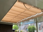 Οριζόντια ρωμαϊκή κουρτίνα premium Decor σε μπεζ χρώμα, τοποθετημένη κάτω από στέγαστρο βεράντας.