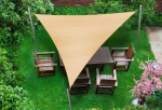 Beige trekantet HDPE solseil 6x6x6 m montert over hagemøbler på en grønn plen.