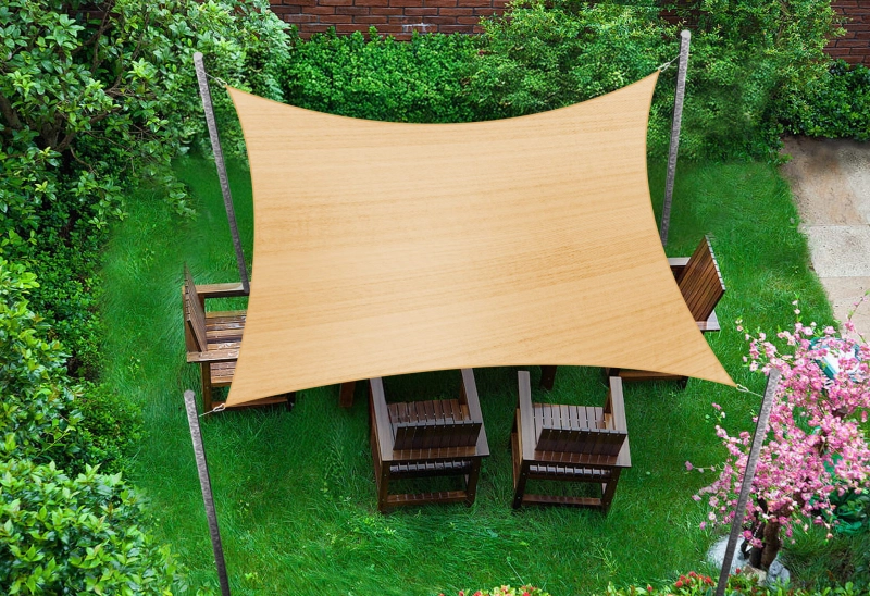 Beige neliönmuotoinen HDPE-aurinkopurje 5x5 m puutarhakalusteryhmän yllä vihreällä nurmikolla.