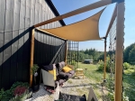 Toldo vela impermeable a medida que protege los muebles de jardín en la terraza de una casa moderna.