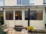 Maßgeschneiderte transparente Terrassenverkleidung mit beigem Rand, montiert auf einer Terrasse oder in einem Pavillon.