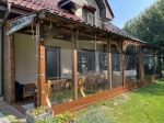 Fermeture de terrasse transparente sur mesure avec bordure marron, montée sur une structure de belvédère en bois.