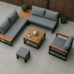 Conjunto de muebles de jardín moderno con cojines grises, mesa de madera y sillón en una terraza de baldosas de gres.