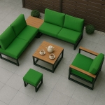 Maßgeschneiderte grüne Gartenkissen auf einem schwarzen Ecksofa, Sessel und Hocker um einen Holztisch.