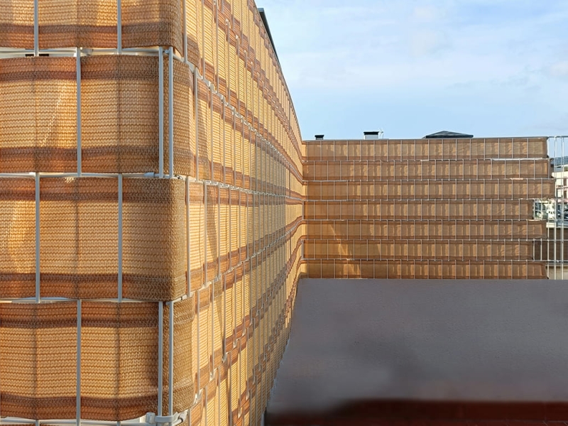 Zandkleurig balkonscherm van HDPE met dicht weefsel, verticaal gevlochten door de metalen balkonhekken.