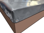 Light grey trailer tarpaulin with metal eyelets, visible on the corner of the cargo bed, made to measure.