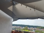 Šedá zahradní plachta voděodolná premium 2x2 napnutá nad balkonem s dekorativními světelnými girlandami.