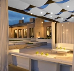 Toldo de pérgola blanco impermeable instalado sobre una terraza de lujo con muebles blancos e iluminación.