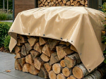 Bâche beige sur mesure pour bois de chauffage, recouvrant une pile de bûches fendues à l'extérieur.