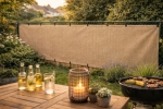 Op maat gemaakte tuinposter van HDPE in beige gemonteerd op een schutting naast de barbecue en tuinmeubelen.