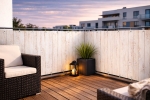 Witte balkonafscherming op maat met houtprint op een modern terras met meubels bij zonsondergang.