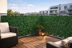 Groen raster balkonzeil op maat met bladvormig motief, gemonteerd op een modern balkon met houten terras.