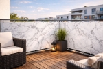 Op maat gemaakte balkonafscherming met marmerlook gemonteerd op metaalhekwerk, balkon met houten vloer en meubels.