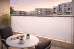 Brise-vue de balcon clair installé sur une rambarde métallique avec vue sur un quartier résidentiel moderne.