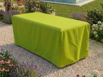 Custom-made green protective cover for a rectangular garden table, placed on light gravel in a garden.