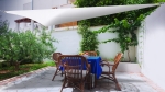 Triangular white garden sail over a table with a blue tablecloth, mounted with a metal fixing kit.