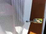 Perdea albă din pachetul marin, fixată cu o carabină de un stâlp de terasă din lemn.