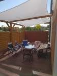 Wit rechthoekig premium waterdicht schaduwdoek 3x4 m boven houten terras met tuinmeubelset.