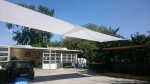 White square premium garden sail 4x4m waterproof stretched over a terrace by the workshop.