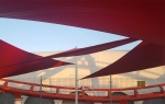 Vela ombreggiante triangolare rossa premium impermeabile 3x3x4,2 montata sopra una pista da corsa per protezione da sole e pioggia.