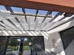 Toldo vela triangular blanco premium impermeable 3,5x3,5x3,5 instalado en una terraza moderna bajo un techo acristalado.