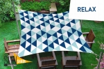 Voile d'ombrage imperméable 3x3 m à triangles géométriques bleus et blancs, suspendue au-dessus des meubles de terrasse.