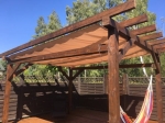 Wasserdichtes ausziehbares Sonnensegel 3x5 m in Beige auf einer Holzpergola mit Hängematte auf der Terrasse.