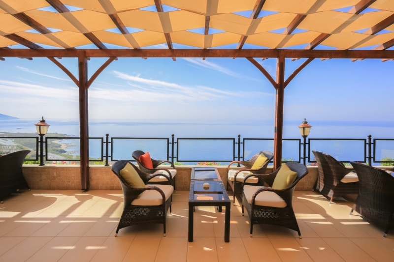 Skræddersyet premium pavillonstribe monteret på en terrassepergola i træ med havudsigt.