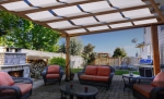 White sun shade sail mounted on a wooden pergola over a garden furniture set on a terrace.