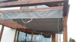 Graue horizontale Raffrollo Premium Decor 3x3 montiert auf einer hölzernen Terrassenpergola.