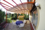 Οριζόντιο premium ρωμαϊκό στόρι Decor 3x4 m τοποθετημένο σε ξύλινη πέργκολα πάνω από βεράντα με έπιπλα.