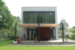Οριζόντια ρωμαϊκή κουρτίνα premium Decor 3x4 τοποθετημένη σε μοντέρνα βεράντα δίπλα σε γυάλινο σπίτι.
