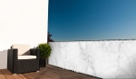 Balkon met donkere wicker fauteuil en balkonafscherming op maat met een elegant wit marmerpatroon.