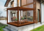 Custom-made white net curtain hanging in a brown terrace pergola next to a modern house with sun loungers.