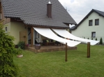 Biely rímsky slnečný pás 2,1x5 m namontovaný na terase rodinného domu nad záhradným nábytkom.