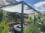 Wit premium schaduwdoek 4x4m gemonteerd op een metalen pergola boven een set tuinmeubelen in de tuin.